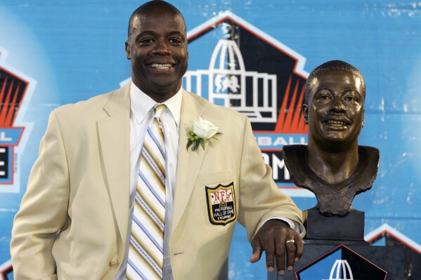 FILE - Former Washington Redskins cornerback Darrell Green stands next to his bronze bust at the Pro Football Hall of Fame in Canton, Ohio, Aug. 2, 2008. The Washington Commanders are retiring Hall of Fame cornerback Darrell Green’s No. 28 next season, the latest step in the organization's efforts to honor players of the past since new ownership took over last summer. The team announced Thursday, April 25, 2024, that Green will be the fifth player in franchise history to receive that honor. (AP Photo/Kiichiro Sato, File)