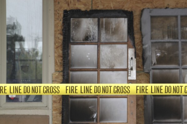 The charred doors that used to make up the entrance to the Republican Party of New Mexico headquarters are propped up behind yellow caution tape in Albuquerque, New Mexico, Monday, March 31, 2025. (AP Photo/Susan Montoya Bryan)