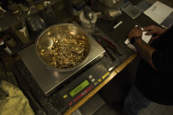 A bowl filled with gold jewelry and a gold bar is weighed at A&M Precious Metals in the St. Vincent Jewelry Center in the Jewelry District of Los Angeles, Friday, May 2, 2025. (AP Photo/Jae C. Hong)