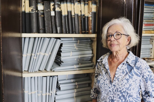 Lilly Duijm poses in front of the boxes of documents from the archive in Paramaribo, Suriname, Friday, May 2, 2025. (AP Photo/Oscar Keur)