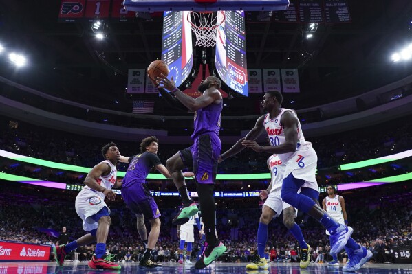 Los Angeles Lakers' LeBron James, center, goes up for a shot past Philadelphia 76ers' Adem Bona during the second half of an NBA basketball game, Tuesday, Jan. 28, 2025, in Philadelphia. (AP Photo/Matt Slocum)
