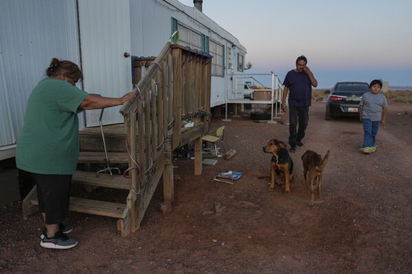 Lorraine Black, left, along with her husband, Ricky Gillis, center, and grandson, Liam Gillis, 7, walk outside their home, Wednesday, Oct. 9, 2024, on the Navajo Nation in Halchita, Utah. (AP Photo/Joshua A. Bickel)