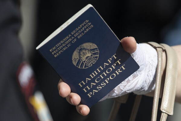 FILE - A woman holds a Belarusian passport as she waits her turn to cast a vote in the Belarusian presidential election, outside the Belarusian Embassy in Moscow, Russia, Sunday, Aug. 9, 2020. Belarus’ authoritarian president banned citizens from renewing their passports while staying abroad, which could force those who fled the country amid growing repression to return to maintain their travel documents. (AP Photo/Pavel Golovkin, File)