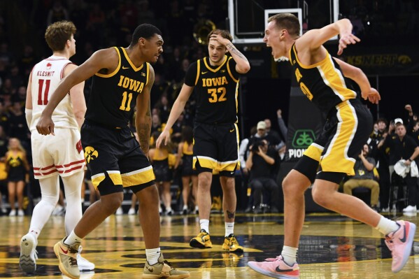 Iowa guard Tony Perkins (11) celebrates his game winning basket with forward Payton Sandfort (20) during overtime in an NCAA college basketball game against Wisconsin, Saturday, Feb. 17, 2024, in Iowa City, Iowa. (AP Photo/Cliff Jette)