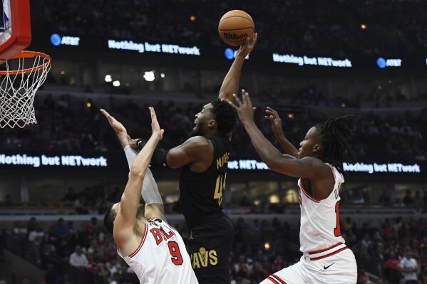Cleveland Cavaliers' Donovan Mitchell, center, goes up to shoot while defended by Chicago Bulls' Nikola Vucevic (9) and Ayo Dosunmu, right, during the first half of an NBA basketball game Saturday, Oct. 22, 2022, in Chicago. (AP Photo/Paul Beaty)