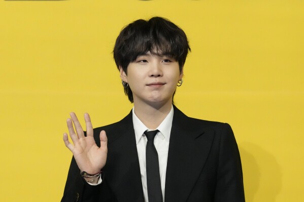 FILE - Suga, a member of South Korean K-pop band BTS, poses for photographers ahead of a press conference to introduce their new single 