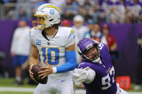 Los Angeles Chargers quarterback Justin Herbert (10) runs from Minnesota Vikings defensive tackle Harrison Phillips (97) during the second half of an NFL football game, Sunday, Sept. 24, 2023, in Minneapolis. (AP Photo/Bruce Kluckhohn)