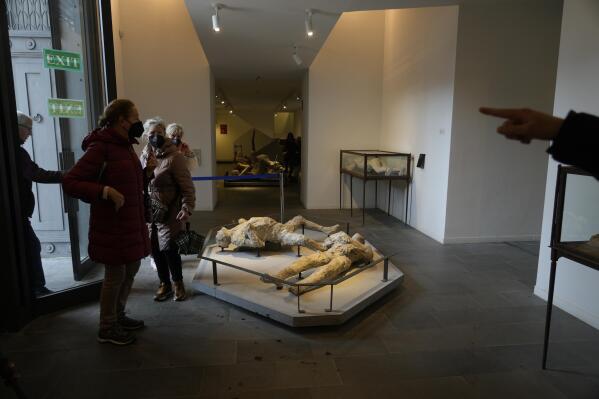 Visitors walk past the casts of some of the victims of the 79 AD Mt. Vesuvius eruption on display at the Pompeii archaeological museums in southern Italy, Tuesday, Feb. 15, 2022. In a few horrible hours, Pompeii went from being a vibrant city to a dead one, smothered by a furious volcanic eruption in 79 AD. Then in this century, Pompeii appeared alarmingly on the precipice of a second death, assailed by decades of neglect, mismanagement, and scanty systematic maintenance of heavily visited ruins. (AP Photo/Gregorio Borgia)