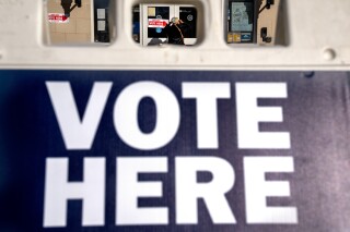 ARCHIVO - A través de un cartel "vota aquí", se observa a una mujer mientras entra en un colegio electoral para votar en las elecciones de mitad de mandato, el 8 de noviembre de 2022, en Washington. (AP Foto/Jacquelyn Martin, Archivo)