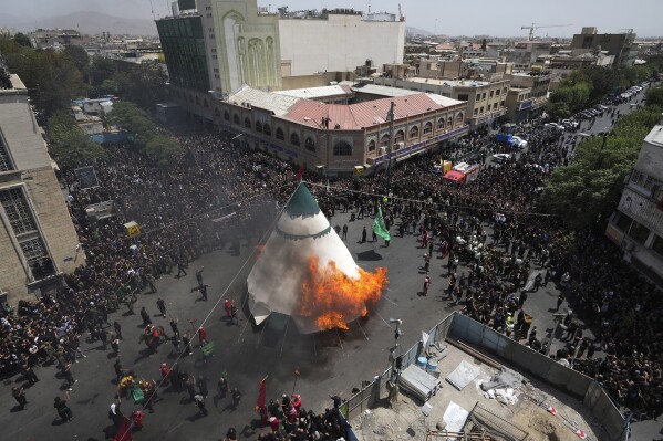 Shiite Muslims burn a tent during a re-enactment of the battle of Karbala in 7th century in present-day Iraq, during Ashoura rituals in downtown Tehran, Iran, Friday, July 28, 2023. Millions of Shiite Muslims around the world on Friday commemorated Ashoura, a remembrance of the 7th-century martyrdom of Imam Hussein, that gave birth to their faith. (AP Photo/Vahid Salemi)