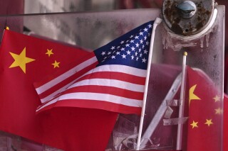 China and U.S. national flags are seen on display on an entrance door of a souvenir shop in Beijing on April 3, 2025. (AP Photo/Andy Wong)
