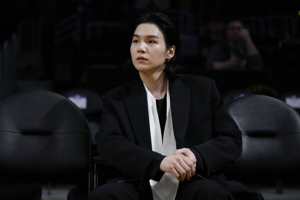 FILE - BTS member Suga attends an NBA basketball game between the Los Angeles Lakers and the Dallas Mavericks on Jan. 12, 2023, in Los Angeles. Suga has become the third member of BTS to begin South Korea’s compulsory military service. BTS' label, Big Hit Music, said in a statement on Monday, Aug. 7, 2023, that Suga 