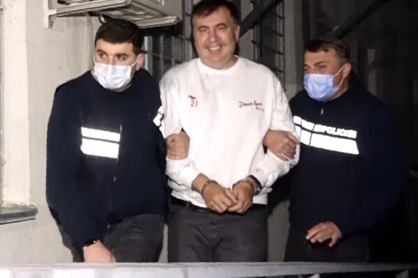 In this handout photo taken from video released by Georgian Interior Ministry Press Service, Georgian Police officers escort former President Mikheil Saakashvili after he was arrested in Rustavi, Georgia, Friday, Oct. 1, 2021. The prime minister of Georgia says former President Mikheil Saakashvili has been arrested. The announcement Friday by Prime Minister Irakli Garibashvili came about 18 hours after Saakashvili, who was convicted in absentia and has lived in Ukraine in recent years, posted on Facebook that he had returned to the country. (Georgian Interior Ministry Press Service via AP)