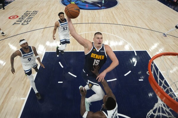 Denver Nuggets center Nikola Jokic (15) goes up for a shot as Minnesota Timberwolves guard Anthony Edwards, bottom, defends during the first half of Game 4 of an NBA basketball second-round playoff series, Sunday, May 12, 2024, in Minneapolis. (AP Photo/Abbie Parr)
