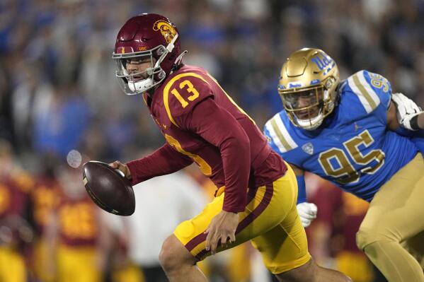 Southern California quarterback Caleb Williams, left, runs with the ball while being chased by UCLA defensive lineman Sitiveni Havili-Kaufusi during the first half of an NCAA college football game Saturday, Nov. 19, 2022, in Pasadena, Calif. (AP Photo/Mark J. Terrill)
