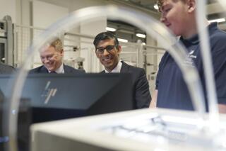 Britain's Prime Minister Rishi Sunak, centre and Grant Shapps, Secretary of State for Energy Security and Net Zero, left, are shown robotics by an apprentice, during a visit to the UK Atomic Energy Authority, Culham Science Centre, for a discussion on energy security and net zero, in Abingdon, England, Thursday March 30, 2023. (Jacob King/Pool Photo via AP)
