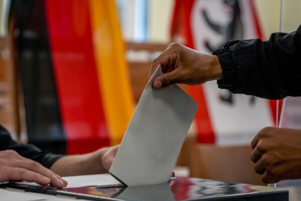 FILE - A man casts his ballot for the German elections in a polling station in Berlin, Germany, Sunday, Sept. 26, 2021. Germany’s Federal Constitutional Court has ordered the 2021 national election to be partially repeated in the German capital because of severe glitches at many polling stations. The court ruled Tuesday that the election must be repeated in 455 of 2,256 constituencies in the state of Berlin, which is one of three German cities that is also a state. (AP Photo/Michael Probst, File)