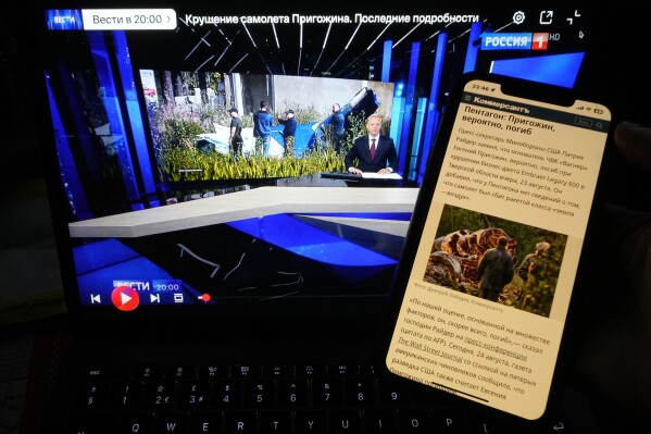 Website of the Russian newspaper Kommersant and TV channel Rossiya 1 showing news that Wagner Group mercenary leader Yevgeny Prigozhin had reportedly been killed in a plane crash are displayed on phone and computer screens in St. Petersburg, Russia, Thursday, Aug. 24, 2023. World media speculates on Prigozhin's presumed death, as Russian state media shies away. (AP Photo/Dmitri Lovetsky)