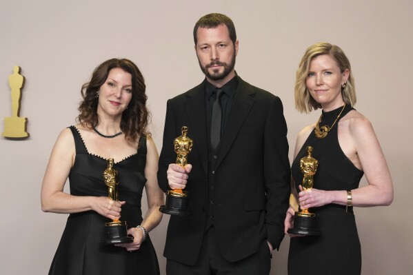 Raney Aronson-Rath, from left, Mstyslav Chernov, and Michelle Mizner pose in the press room with the award for best documentary feature film for "20 Days in Mariupol" at the Oscars on Sunday, March 10, 2024, at the Dolby Theatre in Los Angeles. (Photo by Jordan Strauss/Invision/AP)