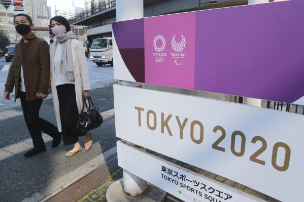 People walk by signage to promote the Olympic Games, in Tokyo, Tuesday, Feb. 16, 2021. The Olympics are scheduled to open on July 23 but recent polls show about 80% of the Japanese public want the Olympics canceled or postponed. (AP Photo/Koji Sasahara)