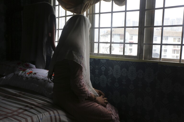 Rohingya child bride, B, age 14, sits on a bed in an apartment in Kuala Lumpur, Malaysia, on Oct. 4, 2023. B came to Malaysia in 2023 to marry an older man. Her husband wants her to get pregnant, but she says she doesn't feel ready. "I still feel like a girl." Deteriorating conditions in Myanmar and in neighboring Bangladesh’s refugee camps are driving scores of underage Rohingya girls to Malaysia for arranged marriages with Rohingya men who frequently abuse them, The Associated Press found in interviews with 12 young Rohingya brides who have arrived in Malaysia since 2022. The youngest was 13. (AP Photo/Victoria Milko)