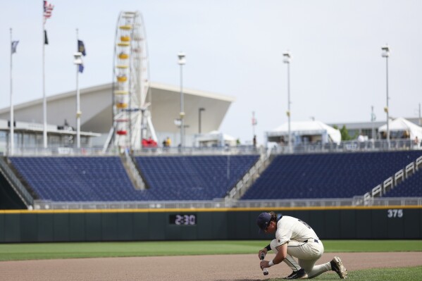 Murray State's Carson Garner scoops up dirt from the infield after his team fell to Arkansas in an NCAA College World Series baseball game at Charles Schwab Field in Omaha, Neb., Monday, June 16, 2025. (Matthew Mueller/Omaha World-Herald via AP)