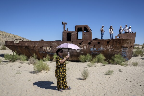 People visit rusted ships near a museum, outside Muynak, Uzbekistan, Friday, July 14, 2023. (AP Photo/Ebrahim Noroozi)