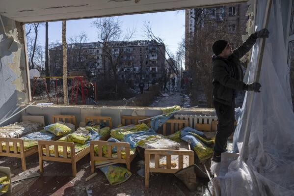 FILE - A man removes a destroyed curtain inside a school damaged among other residential buildings in Kyiv, Ukraine, Friday, March 18, 2022. As of early May, the Ukrainian government says Russia has shelled more than 1,000 schools, completely destroying 95. (AP Photo/Rodrigo Abd, File)