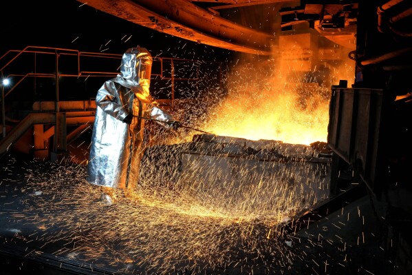A worker in a protective suit pokes a metal rod to tap slag from a smelting furnace at PT Vale Indonesia's nickel processing plant in Sorowako, South Sulawesi, Indonesia, Tuesday, Sept. 12, 2023. As demand for materials needed for batteries, solar panels and other components vital for cutting global emissions rises, carbon emissions by miners and refiners will likewise rise unless companies actively work to decarbonize. (AP Photo/Dita Alangkara)