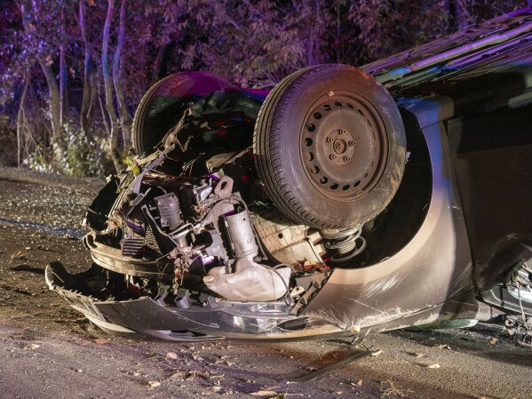 A car lays on the road after an accident near Kiskunmajsa, Hungary, Thursday, Oct. 12, 2023. Two people were killed and six other injured in a car accident in Hungary early Thursday after a vehicle suspected of transporting illegal migrants hit a tree and overturned. (AP Photo/Ferenc Donka)