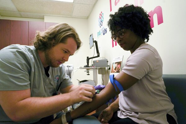 
              In this Aug. 7, 2017, photo, Kenneth Parker Ulrich, left, a research technician at the University of Pittsburgh Medical Center, inserts a needle to collect a blood sample from Erricka Hager, a participant in the "All of Us" research program in Pittsburgh. The "All of Us" research program is run by the National Institutes of Health and plans to track the health of at least 1 million volunteers by 2019. By doing so, researchers hope to learn how to better tailor treatments and preventative care to people's genes, environments, and lifestyle. The University of Pittsburgh is running a pilot program with some of the first enrollees in the study. (AP Photo/Dake Kang)
            
