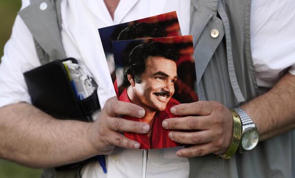 A guest holds programs during the unveiling of a memorial sculpture of the late actor Burt Reynolds at Hollywood Forever Cemetery, Monday, Sept. 20, 2021, in Los Angeles. Reynolds died in 2018 at the age of 82. (AP Photo/Chris Pizzello)