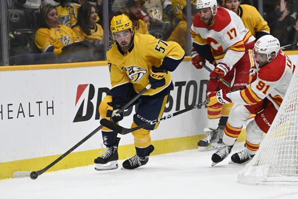 Nashville Predators defenseman Dante Fabbro (57) moves the puck ahead of Calgary Flames center Nazem Kadri (91) during the first period of an NHL hockey game Monday, Jan. 16, 2023, in Nashville, Tenn. (AP Photo/Mark Zaleski)