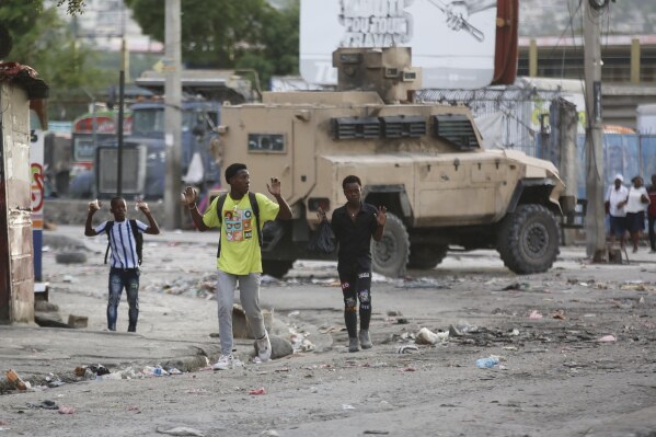 Youths raise their hands to show police they are not carrying weapons during an anti-gang operation at the Portail neighborhood in Port-au-Prince, Haiti, Thursday, Feb. 29, 2024. Gunmen shot at the international airport and other targets in a wave of violence that forced businesses, government agencies and schools to close early. (AP Photo/Odelyn Joseph)