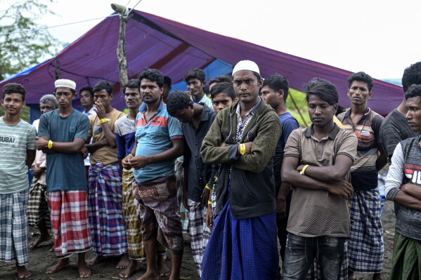 Mohammed Zubair, fourth from right, wearing a white cap, stands with other ethnic Rohingya near a tarpaulin tent where they have been sheltering since landing on Dec. 10 in Pidi, Aceh province, Indonesia, Saturday, Dec. 16, 2023 Are.  (AP Photo/Reza Saifullah)
