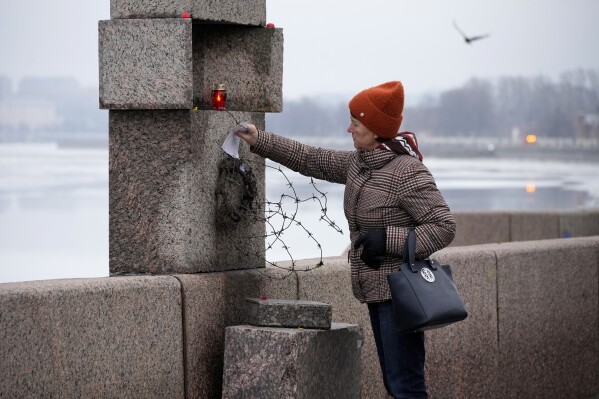Một người phụ nữ đặt một mảnh giấy với những lời đau buồn dành cho Alexei Navalny bày tỏ lòng kính trọng cuối cùng với ông tại Đài tưởng niệm các nạn nhân của sự đàn áp chính trị ở St. Petersburg, Nga, Thứ Bảy, ngày 24 tháng 2 năm 2024. Navalny, 47 tuổi, người Nga tốt nhất - chính trị gia đối lập nổi tiếng, bất ngờ qua đời vào ngày 16/2 tại trại giam, khiến hàng trăm người Nga trên khắp đất nước đổ về các đài tưởng niệm đầy ngẫu hứng với hoa và nến. (Ảnh AP/Dmitri Lovetsky)