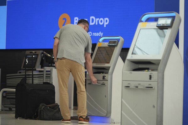A traveller collects a boarding pass at one of the check-in kiosks at the Southwest Airlines counter in the main terminal of Denver International Airport Friday, May 23, 2025, in Denver. (AP Photo/David Zalubowski)