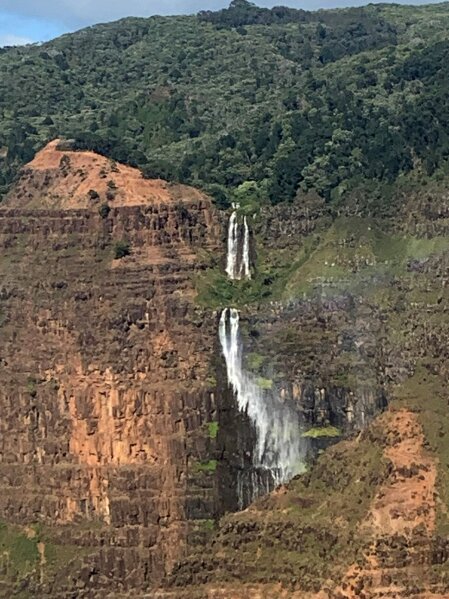 This Dec. 17, 2019, aerial photo shows a waterfall on the Na Pali Coast on the island of Kauai in Hawaii. The Coast Guard is searching for a tour helicopter that disappeared on the Na Pali Coast with seven people aboard on Thursday, Dec. 26, 2019. Authorities say the helicopter's owner called for help about 45 minutes after the chopper was due back from the tour. (AP Photo/Maryclaire Dale)