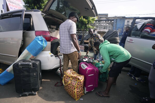 A worker loads a vehicle with luggage belonging to a passenger traveling for Christmas, in Lagos, Nigeria, Wednesday, Dec. 20, 2023. (AP Photo/Sunday Alamba)