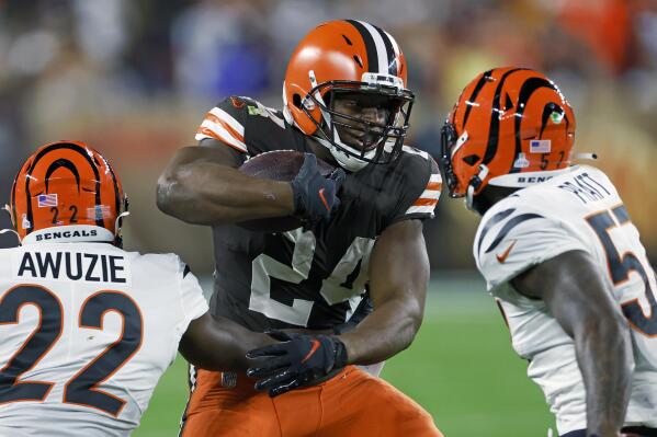 Cleveland Browns running back Nick Chubb (24) carries the ball with Cincinnati Bengals cornerback Chidobe Awuzie (22) and linebacker Germaine Pratt (57) defending during the first half of an NFL football game in Cleveland, Monday, Oct. 31, 2022. (AP Photo/Ron Schwane)