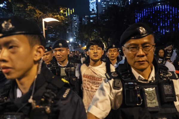 A man, center, is escorted by police officers at the Victoria Park, the city's venue for the annual 1989 Tiananmen massacre vigil, on the 36th anniversary of China's Tiananmen Square crackdown, in Hong Kong, Wednesday, June 4, 2025. (AP Photo/Chan Long Hei)