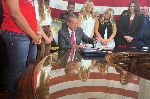 Nebraska Gov. Jim Pillen is flanked by supporters Wednesday, June 4, 2025 as he signs into law a bill banning transgender athletes from girls' sports. (AP Photo/Margery Beck)