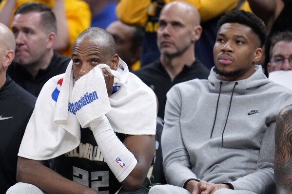 Milwaukee Bucks forward Khris Middleton (22) watches from the bench with teammate Giannis Antetokounmpo, right, during the second half against the Indiana Pacers in Game 6 in an NBA basketball first-round playoff series, Thursday, May 2, 2024, in Indianapolis. (AP Photo/Michael Conroy)