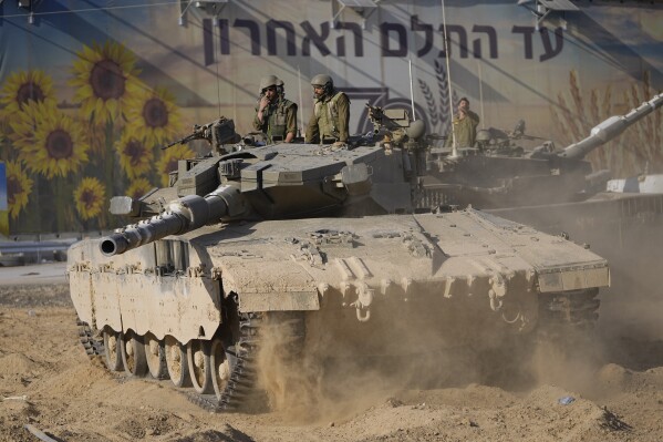 Israeli soldiers move a tank at a staging area near the border with the Gaza Strip in southern Israel on Sunday, Oct. 15, 2023. (AP Photo/Ohad Zwigenberg)