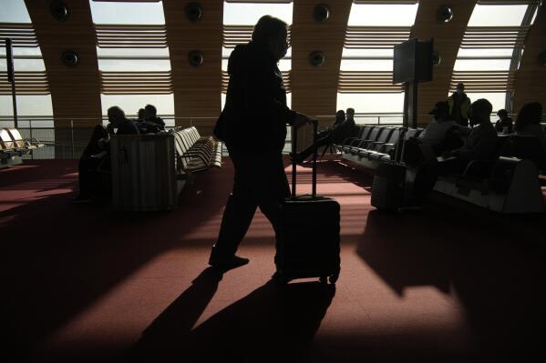 A passenger for United States wheels his luggage in the waiting zone before boarding a flight in the Charles de Gaulle airport, north of Paris, Monday, Nov. 8, 2021. The U.S. lifted restrictions Monday on travel from a long list of countries including Mexico, Canada and most of Europe, allowing tourists to make long-delayed trips and family members to reconnect with loved ones after more than a year and a half apart because of the pandemic. (AP Photo/Christophe Ena)