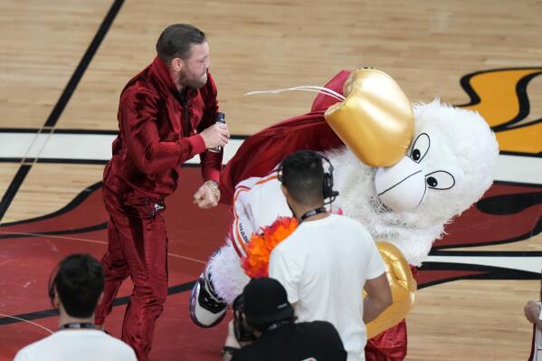 Former MMA fighter Conor McGregor punches Burnie, the Miami Heat mascot, during a break in Game 4 of the basketball NBA Finals against the Denver Nuggets, Friday, June 9, 2023, in Miami. The man who occupies Burnie's costume needed medical attention. (AP Photo/Lynne Sladky)