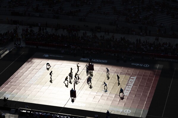 Players are silhouetted as sunlight reflects off the court during a college volleyball match between Nebraska-Kearney and Wayne State on Wednesday, Aug. 30, 2023, in Lincoln, Neb. (Kenneth Ferriera/Lincoln Journal Star via AP)