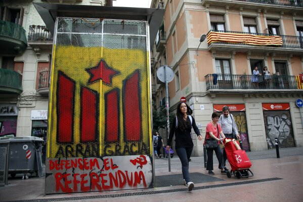 
              People walk past a graffiti of a Gracia neighborhood pro-independence youth organization in Barcelona Saturday, Sept. 30 2017. Catalonia's planned referendum on secession is due to be held Sunday by the pro-independence Catalan government but Spain's government calls the vote illegal, since it violates the constitution, and the country's Constitutional Court has ordered it suspended. (AP Photo/Bob Edme)
            