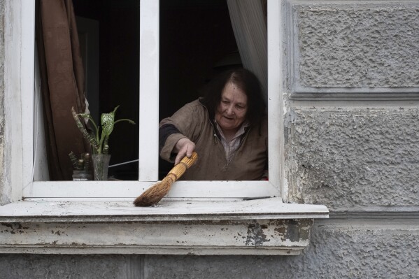 A woman cleans her window after a Russian missile strike on Sumy, Ukraine, Sunday April 13, 2025. (AP Photo/Volodymyr Hordiienko)