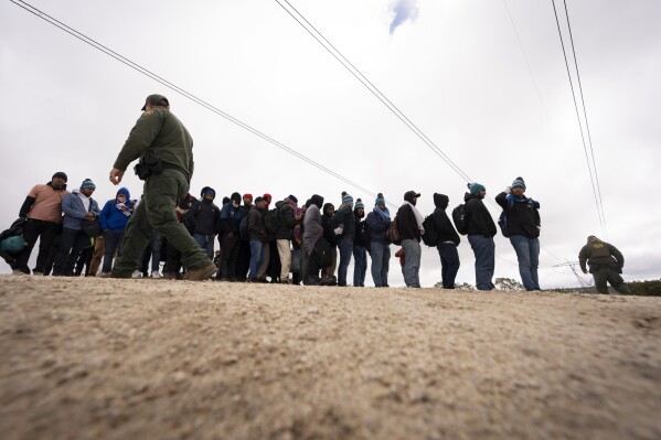 FILE - Men seeking asylum, including Peruvians, line up as they wait to be processed after crossing the border with Mexico nearby, on April 25, 2024, in Boulevard, Calif. President Joe Biden has ordered a halt to asylum processing at the U.S. border with Mexico when arrests for illegal entry top 2,500 a day, which was triggered immediately. (AP Photo/Gregory Bull, File)